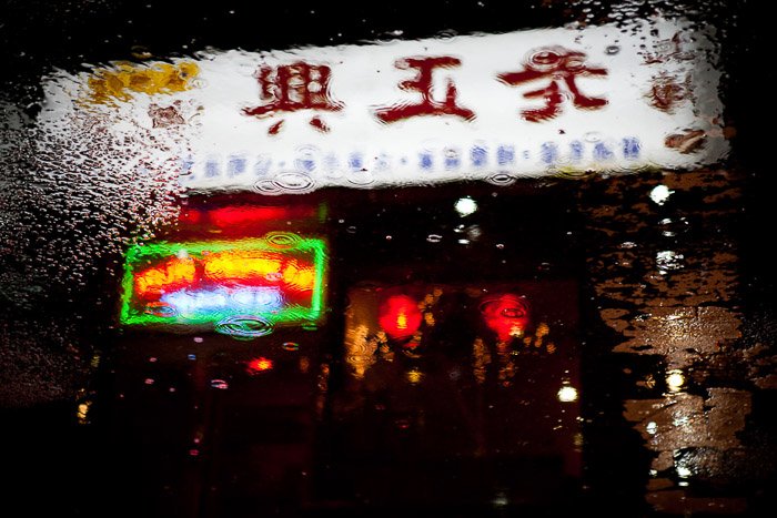 街上水坑里倒映着霓虹灯招牌的中国外卖。城市夜间摄影