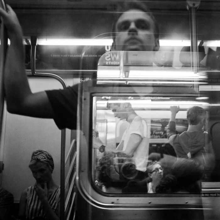 Self portrait reflection taken in subway overlaying reflection and image. Photographed in black and white monochrome.