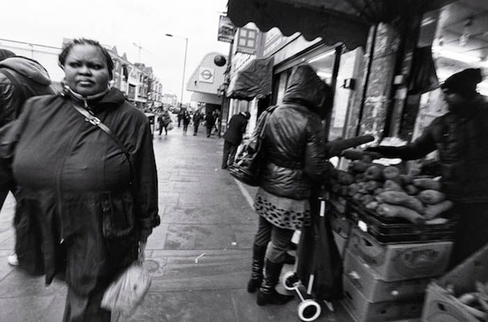  Un portrait de rue d'une femme marchant dans la rue pendant que d'autres achètent des légumes 