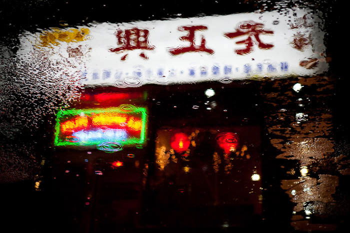 A reflection of a Chinese restaurant in a puddle on the street