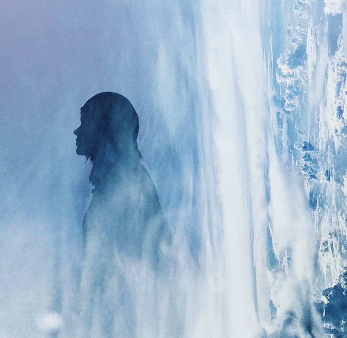 A silhouette of a woman double exposed with an image of clouds