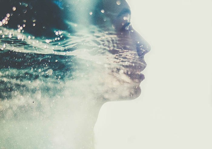 Creative double-exposure of a young woman's profile and water drops