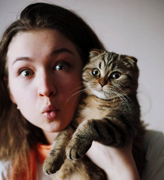 Cute self-portrait photo of a girl and cat making silly faces.