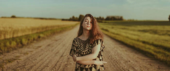 A self portrait picture of a redheaded woman standing on a road.