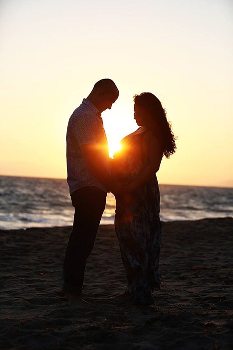 photo of a couple on a beach with the sun setting in the background