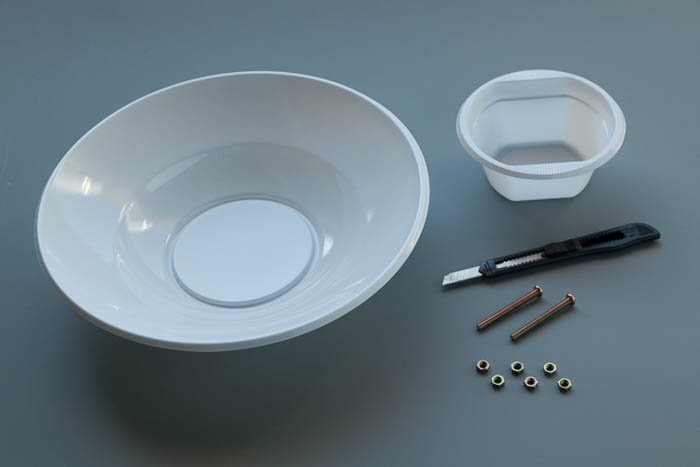 A plastic bowl, a smaller plastic salad bowl, two bolts, six nuts and an X-Acto knife to make a DIY photography lighting beauty dish