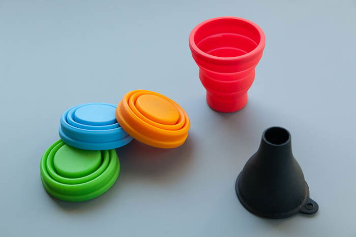 Red silicone cups and lids in assorted colors and a black funnel for DIY photography speedlight modifiers