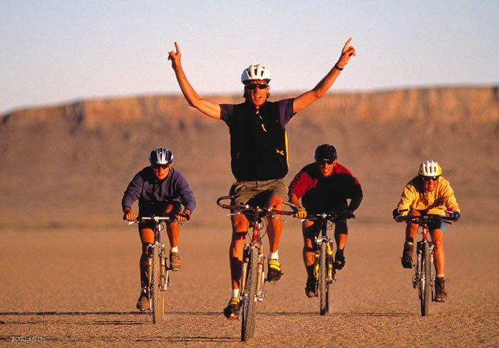 four men bicycling in a desert