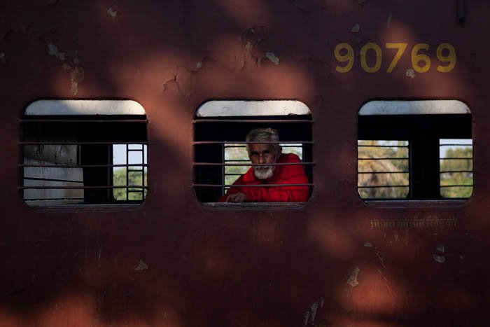 街头摄影的取景:一个男人从火车车厢的窗户向外看的照片