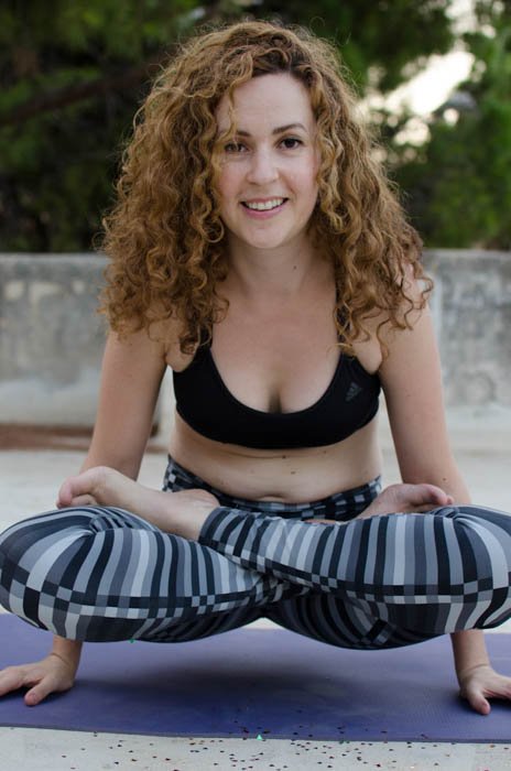 Yoga photography showing a model in an arm balancing pose, looking straight at the camera
