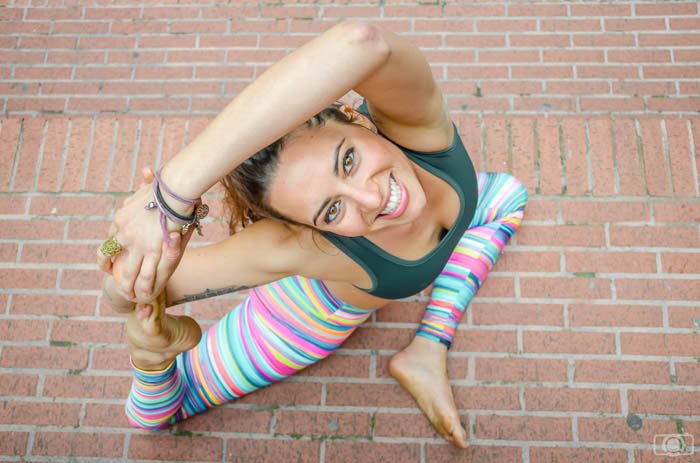 high angle photo of a yoga model wearing bright leggings and smiling up at the camera