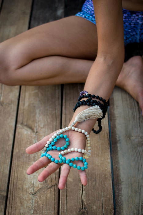 Close-up photo of mala beads in a female model's hand