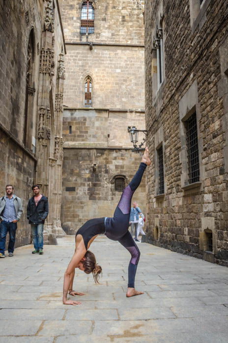 girl performing one-legged yoga wheel pose on the street