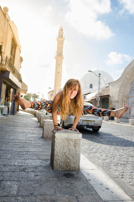 Girl performing a balancing yoga pose on sidewalk guardrail