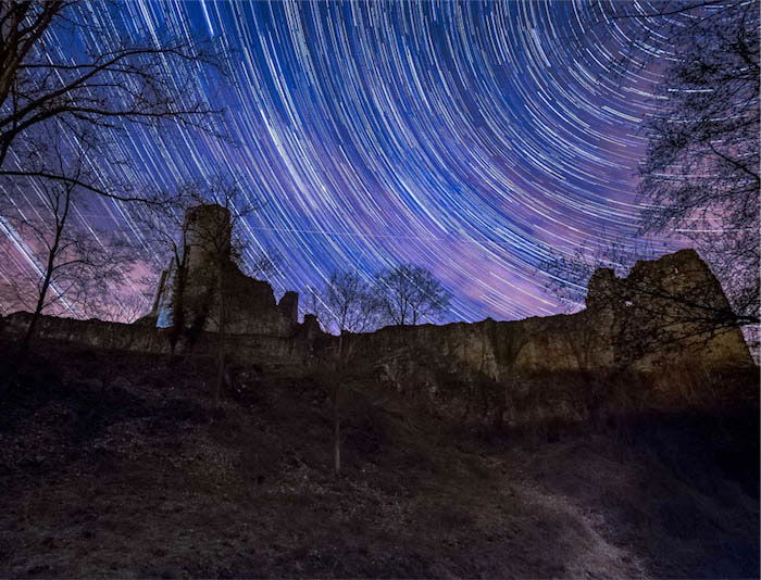 Star trails above a stone building