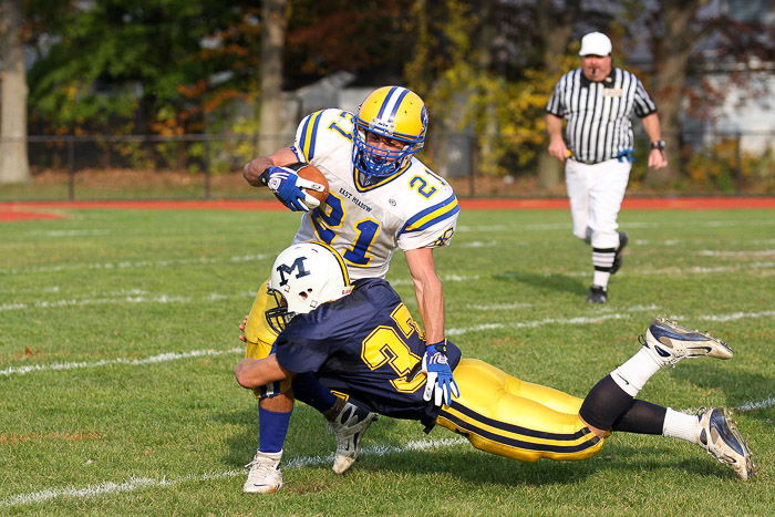 Football players in the middle of a flying tackle