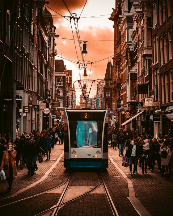 een oranje en cyaan getinte straatfotografie opgenomen met een tram en menigten