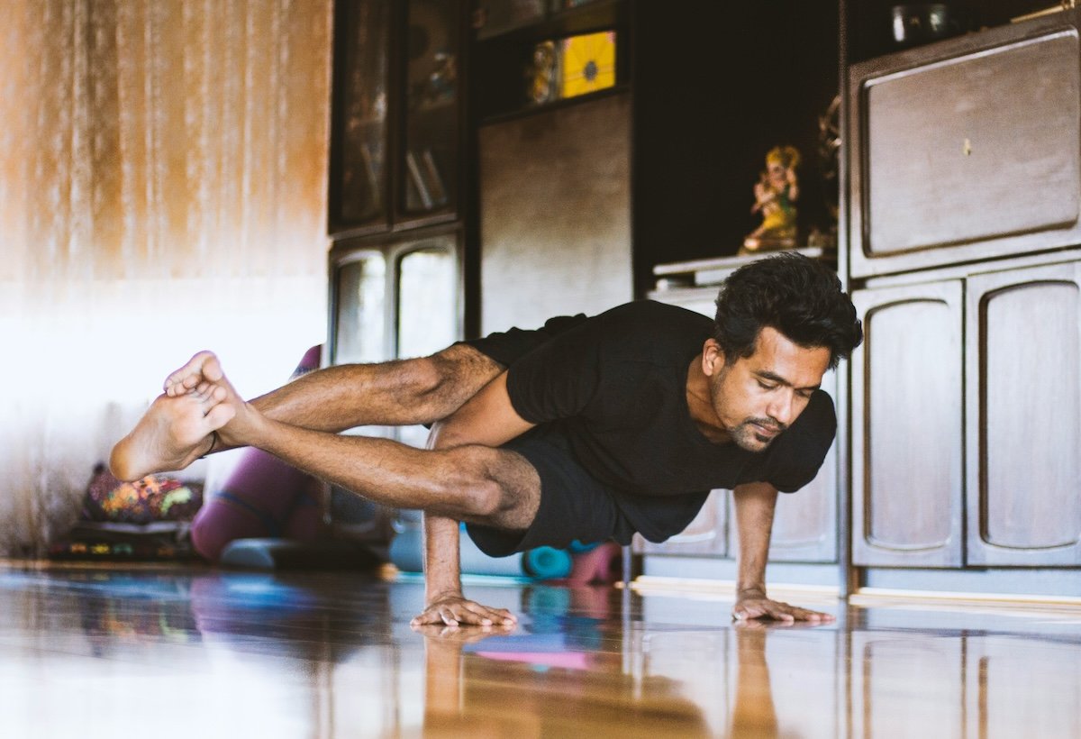 A man doing an arm balance side-crow pose shot a low angle as an example of yoga photography