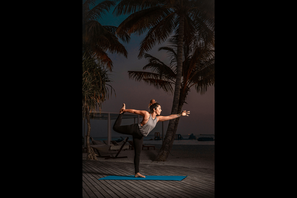 Yogini doing a dancers pose outside at night as an example of yoga photography
