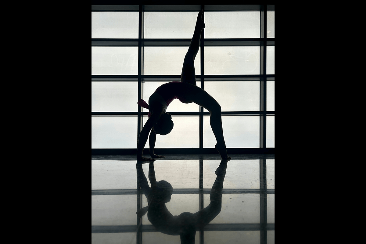A yogini doing a back bend against a window creating a silhouette as an example of creative yoga photography