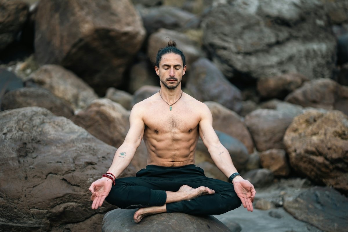 Yogi doing a sukhasana sitting pose on rocks as an example of yoga photography
