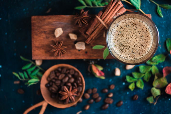 A warm drink is accompanied by autumnal decor and spices on a dining table. 