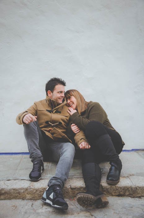 Relaxed photo of a couple sitting on the grounds smiling and holding each other