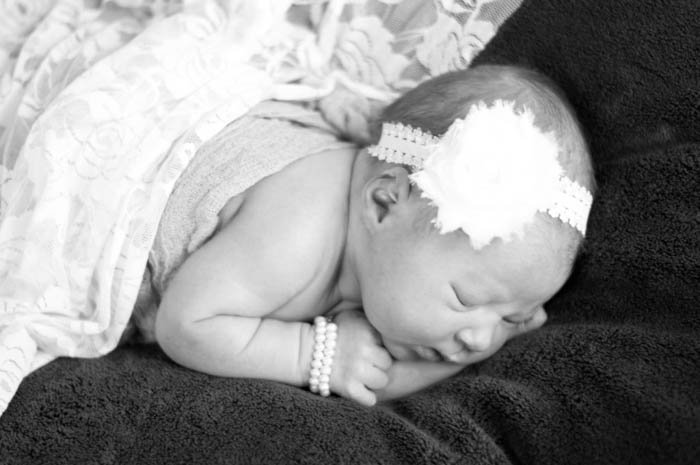 traditional newborn photo of sleeping baby on blankets with headband and pearl bracelet