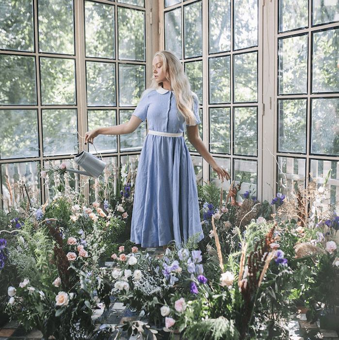 Woman in greenhouse watering flower and plants around her