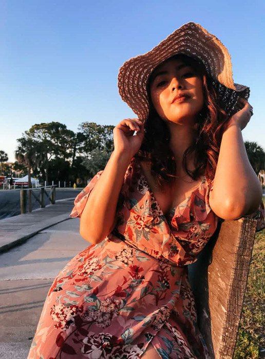 A female model posing outdoors in a sun hat