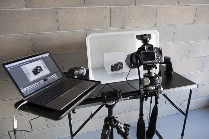 A diy photoshoot setup containing a laptop, diy White Box Flash Diffuser, dslr camera on tripod