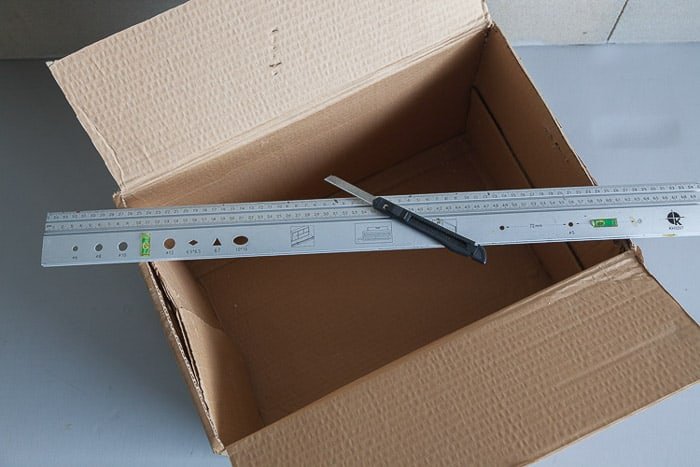 Overhead shot of an open cardboard box, ruler, and X-Acto knife you need to make your own photography light box