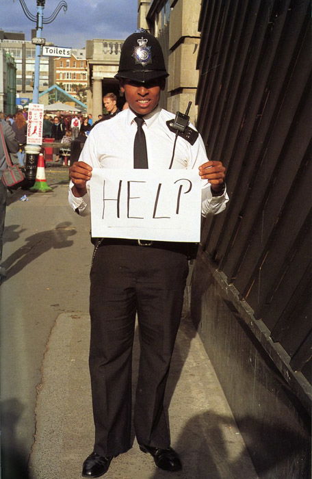 A policeman holding a sign that says help by Gillian Wearing