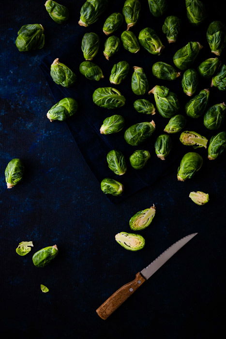 Raw green Brussel sprouts and a knife. 