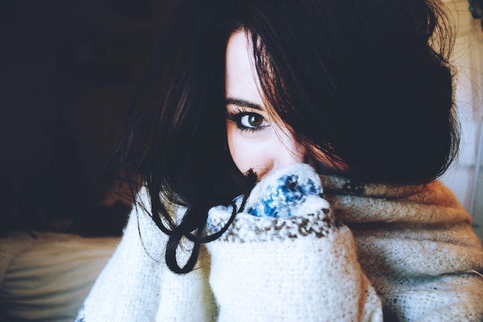 Self-portrait of woman in a sweater sitting in a home studio