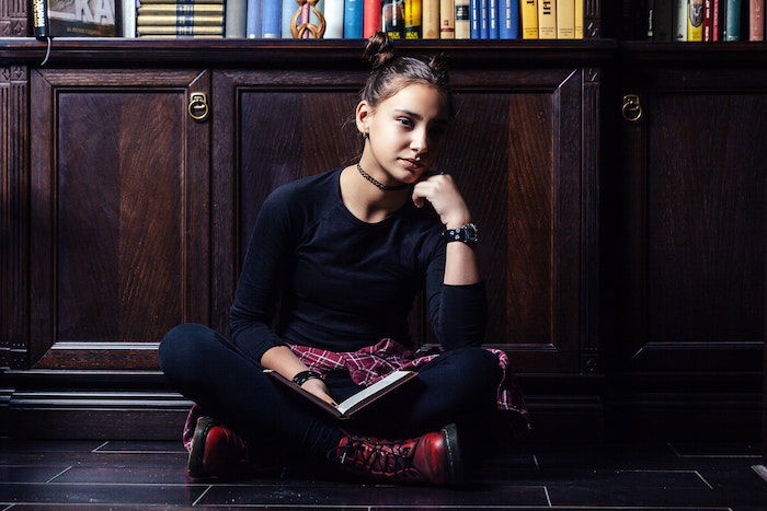 Self-portrait of a woman sitting and reading a book in a library