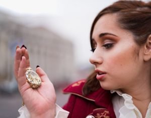 portrait photo of a girl holding a pocket watch with a shallow depth of field