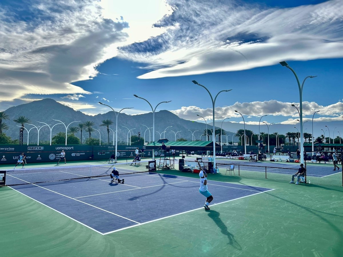 An outdoor tennis court with a match being played as an example of sports photography