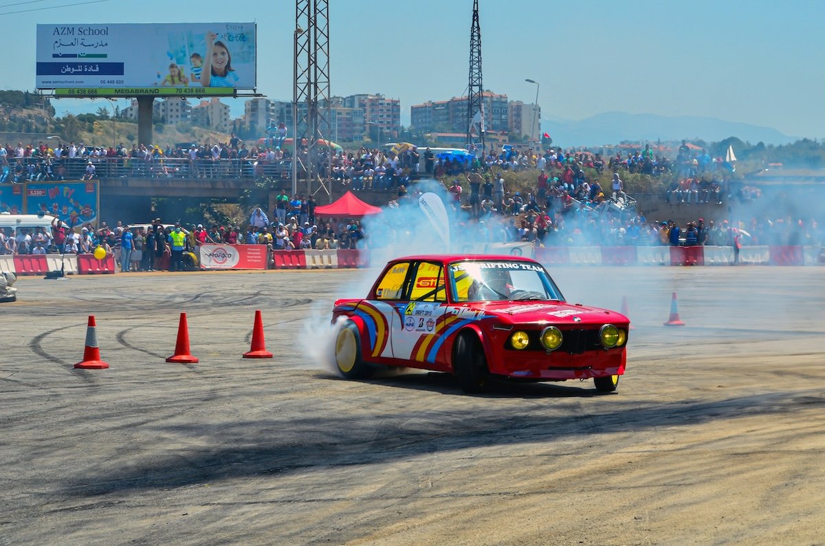 A rally racing car taking a turn at high speed with smoke coming from its rear wheels as an example for sports photography