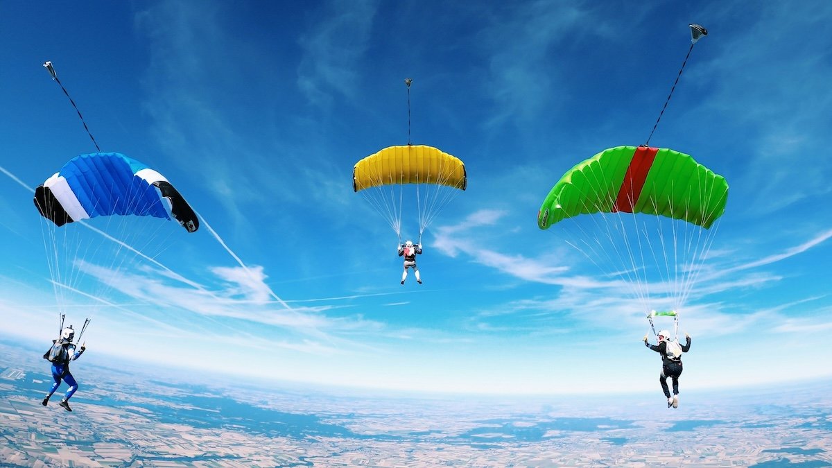 Three skydivers parachuting down as an example for sports photography