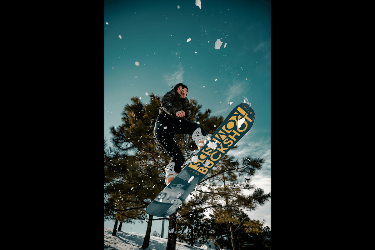 A snowboarder doing a jump in the air with snow flying as an example for sports photography