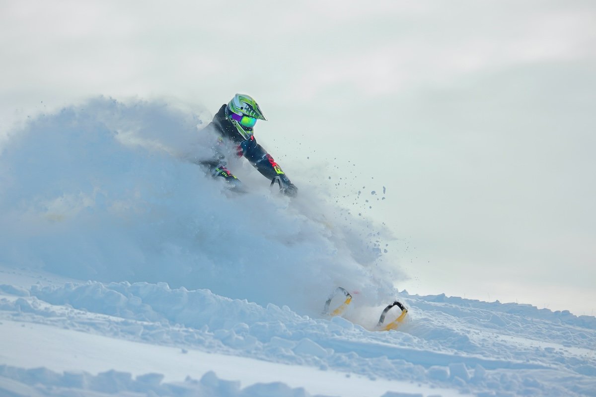 A snowmobiler racing in the snow as an example of sports photography