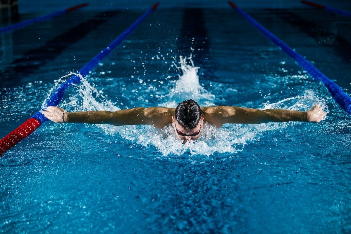 Swimmer performing the butterfly stroke in a professional swimming pool as an example for sports photography