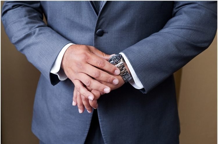 man in a navy suit looking at his watch