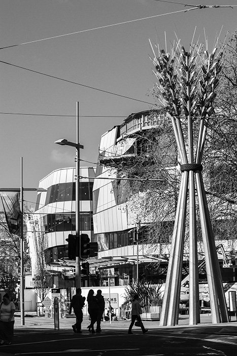 Black and white photo of a New Zealand street scene including the sculpture 'Flour Power' by Regan Gentry, buildings and people. Architecture Photography.
