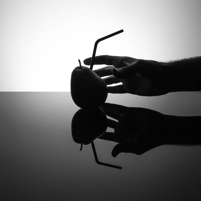 Shadowy commercial-style photo with a straw stabbed into a pear