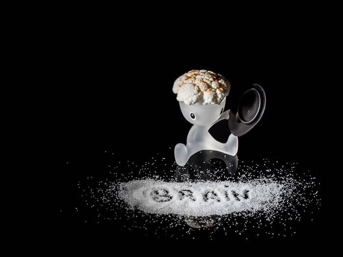 Una fotografía creativa de naturaleza muerta con una huevera Alessi, coliflor y sal
