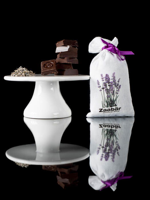 Squares of chocolate on a cake stand with a lavender bag next to it