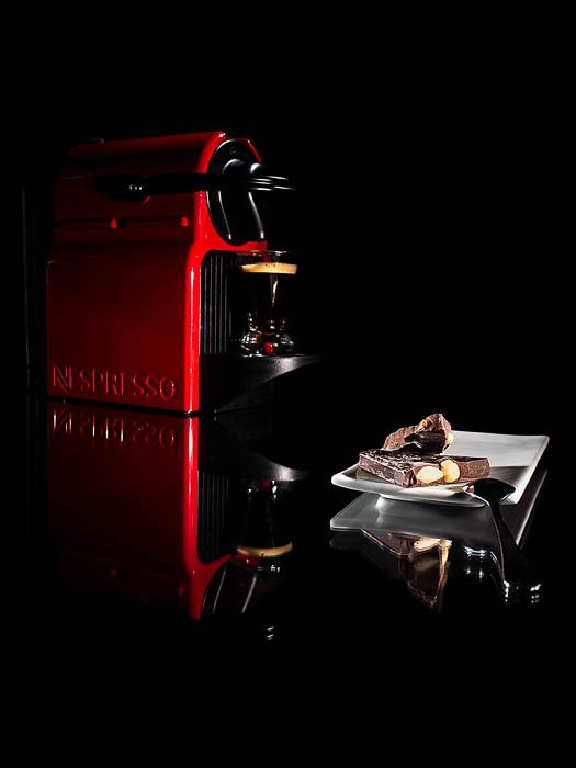 A commercial style photo of a Nespresso coffee machine beside a small plate of chocolates
