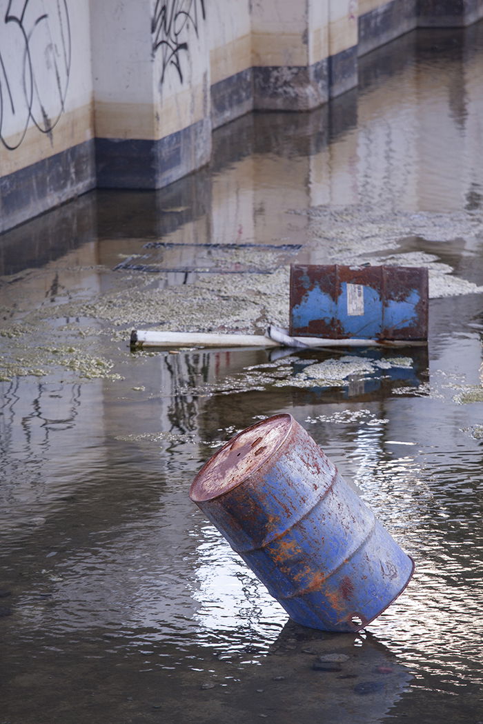 rusty blue waste barrels floating in a river